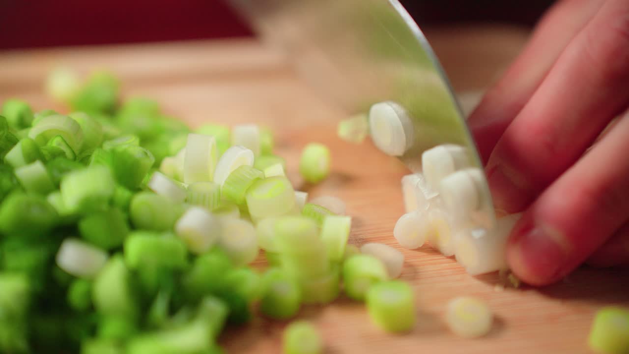Cutting up green onion by hand on cutting board