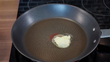 butter melting and sliding in a heated frying pan on the stove