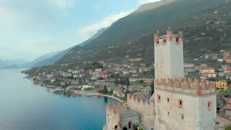 Imágenes-De-Drones-Que-Muestran-La-Torre-Del-Castillo-De-Malcesine-En-El-Lago-De-Garda,-Italia,-Mostrando-Turismo,-Vacaciones,-Naturaleza,-Agua,-Cielo-Azul-Y-Vegetación.