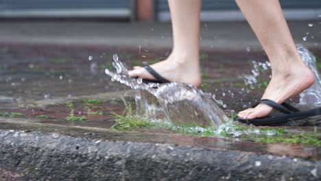 a flipflops feet running on the paving footpath on raining day, on the street side walk, flooding street, with rain and water, lower body part, rush hurry run finding the shelter to hide the rain