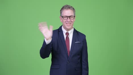 happy mature businessman with eyeglasses waving hand