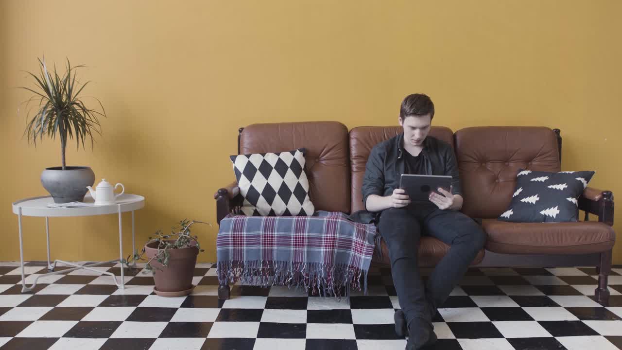 hombre usando una tableta en un sofá