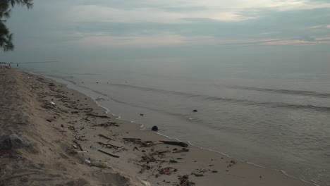 Natürliche-Trümmer-Und-Abfälle-Wurden-An-Einem-Frühen-Morgen-An-Einer-Strandküste-Angespült,-Das-Ferne-Wetter-Sah-Mit-Sich-Nähernden-Monsunwolken-Bedrohlich-Aus,-Cha-Am,-Phetchaburi,-Thailand