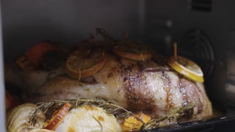 roast duck with herbs and lemon roasting in oven