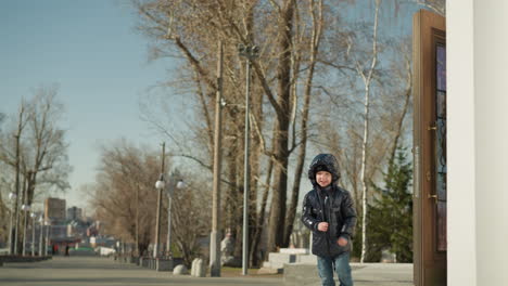 cerca de un niño saliendo de la puerta con las manos abiertas felizmente viniendo a abrazar a alguien, con una calle alineada con postes de luz y edificios en el fondo