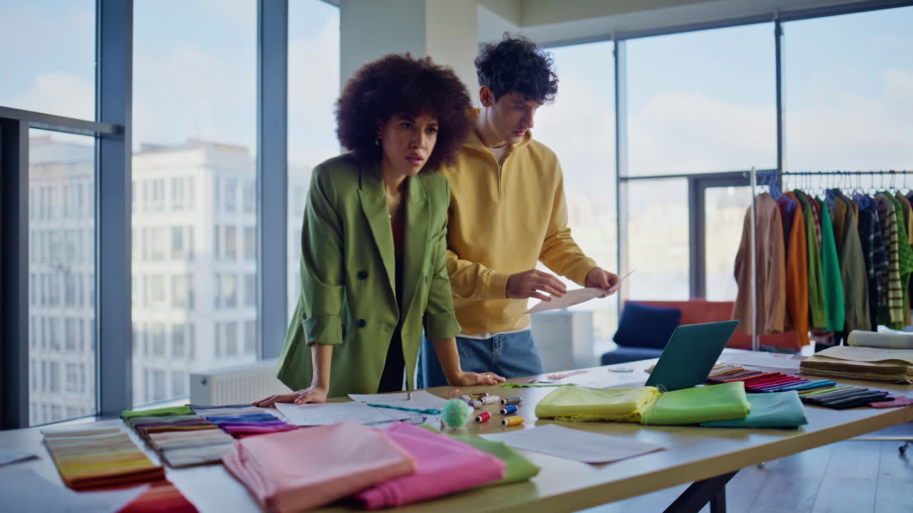 Designers team collaborating collection choosing fabric samples at work desk