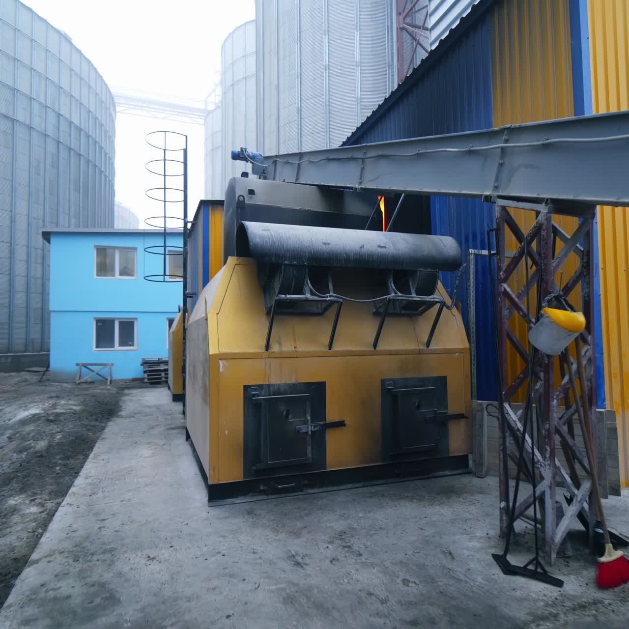 Exterior of the elevator furnace premises with a long orthogonal tube. View of the exterior with gradual distancing. Huge tanks at the backdrop