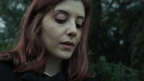 young woman looks worriedly at a book reading under a tree in nature