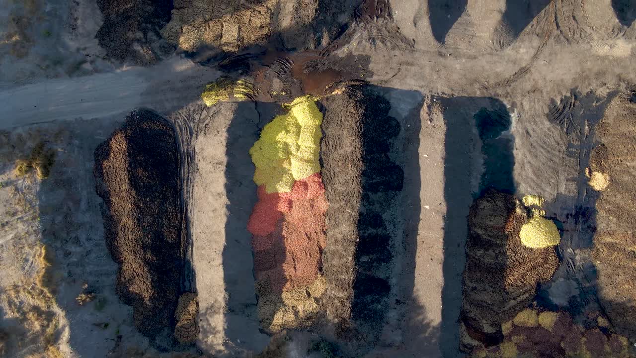 낮에 농장 밭에 있는 농장으로 둘러싸인 퇴비 지역에 버려진 오렌지 껍질을 공중에서 아래로 닫습니다