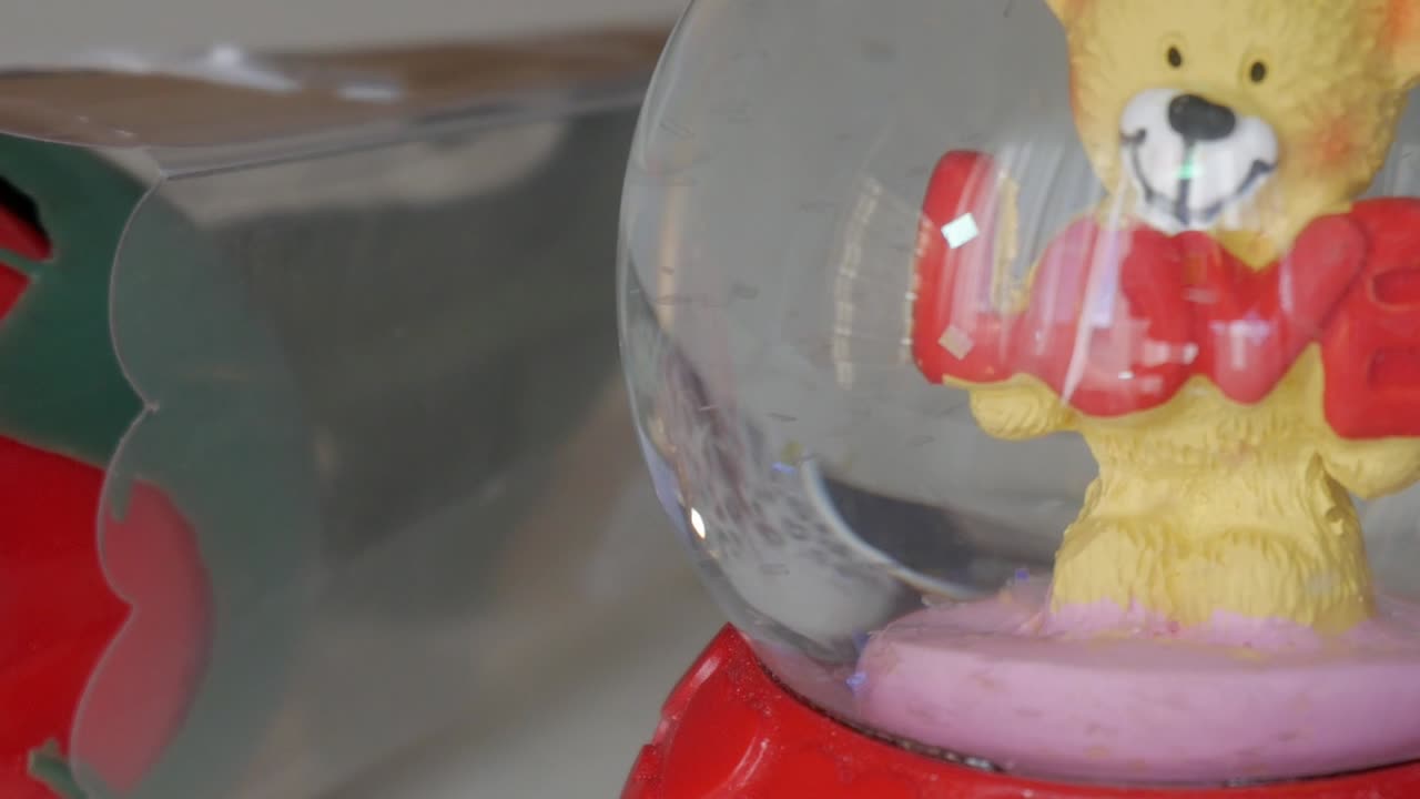 A teddy bear holding the word "LOVE" in a Valentine's Day-themed snow globe