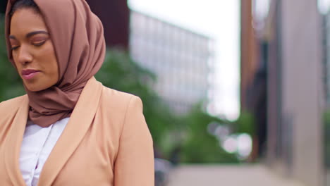 primer plano de una mujer de negocios musulmana moderna con hijab caminando hacia el trabajo en la oficina mirando el teléfono móvil