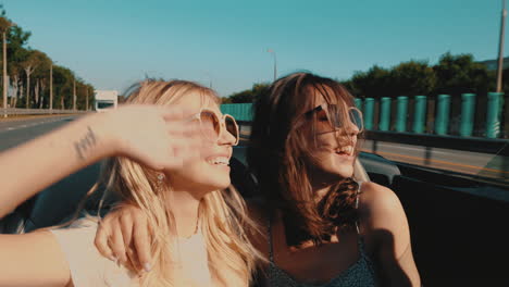 two happy friends enjoying a road trip in a convertible