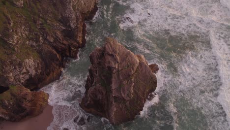 Big-rock-at-Praia-da-Ursa-Portugal-surround-by-the-ocean-top-down-shot,-aerial