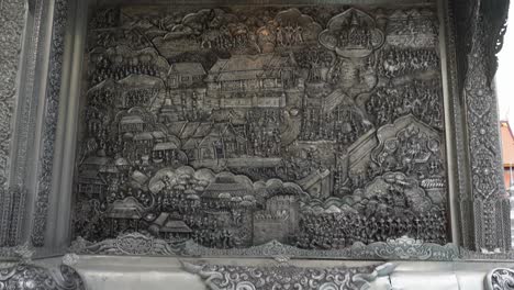 thailand,chiang mai,tilt up slowly over the amazing silver reliefs,outside of the famous silver temple,wat si supan. amazing silversmithing art.