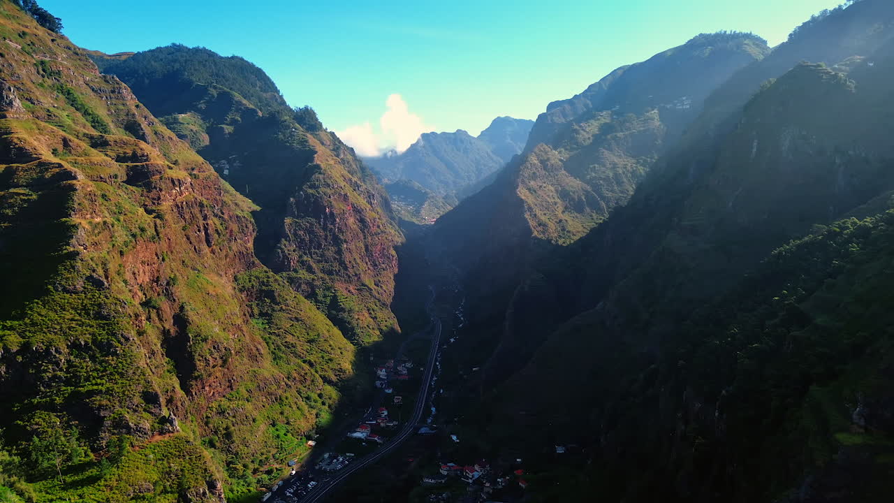 High mountains hide the little town. A highway crosses the city of Madeira Islands, Portugal. Aerial view.
