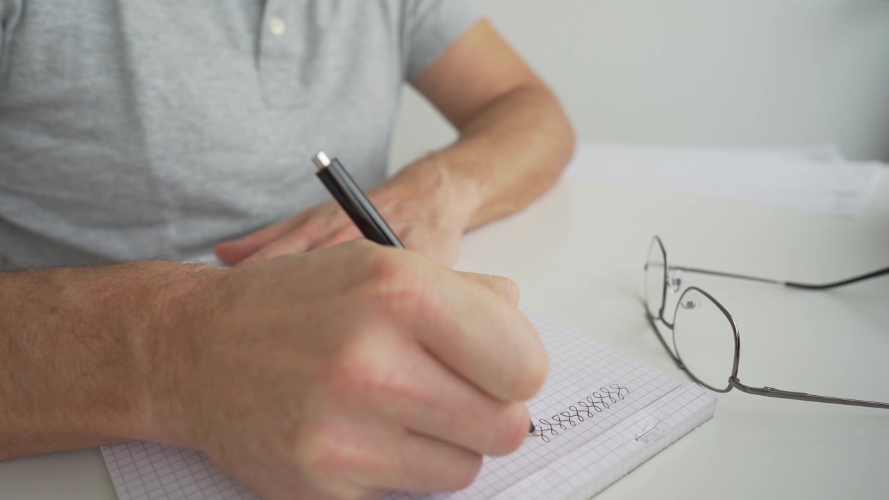 Uomo che disegna su una scrivania sul suo blocco note.