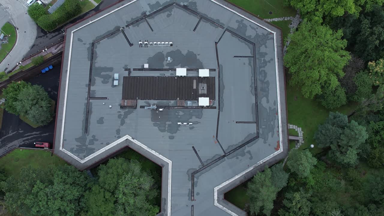 Top-down drone shot of Olivetti’s historic company canteen in Ivrea, designed to harmonize with nature, surrounded by dense forest, example of humane modernist industrial architecture, , slow motion