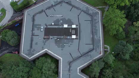 top-down drone shot of olivetti’s historic company canteen in ivrea, designed to harmonize with nature, surrounded by dense forest, example of humane modernist industrial architecture, , slow motion