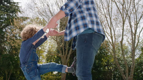 happy father and son playing together in backyard garden happy little boy having fun with dad holding child playfully swinging his kid enjoying childhood freedom outdoors 4k