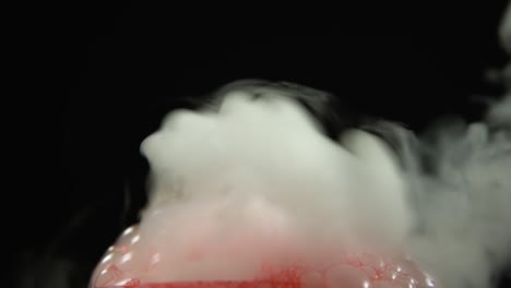chemical reaction dry ice with red blood bubbles and smoke on a black background. closeup