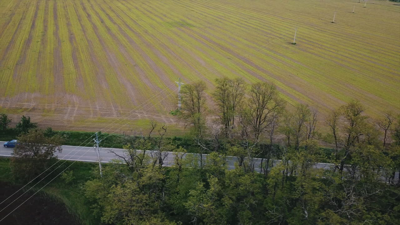 낮 동안 마을 풍경 근처의 아름다운 농지에서 교차로가 있는 도로에서 운전하는 자동차