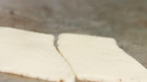 rebanadas de queso halloumi colocadas en una parrilla con manos enguantadas