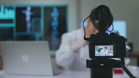 asian scientist man taking solution from test tube with micropipette putting in petri dish and using camera on tripod recording video