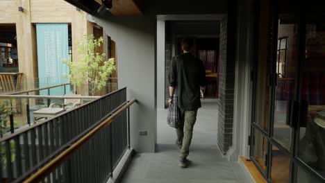 person walking along an outdoor building corridor