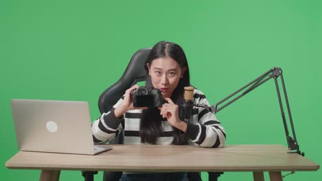 woman vlogger holding camera in front of green screen