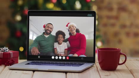 Glückliche-Familie-Mit-Weihnachtsmützen-Bei-Einem-Laptop-Videoanruf,-Mit-Weihnachtsdekorationen-Und-Baum