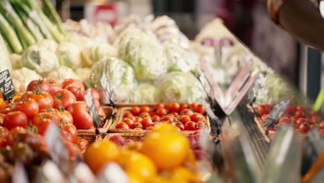 Close-up-shot-of-a-Black-man-in-a-plaid-shirt-choosing-vegetables-at-a-supermarket-counter.-View-of-juicy-and-rich-summer-vegetables.-Video-filmed-in-high-quality