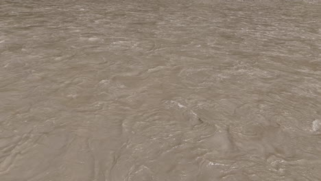 landscape drone shot of a river during monsoon in nepal, with heavy rainfall causing flooding on a sunny day