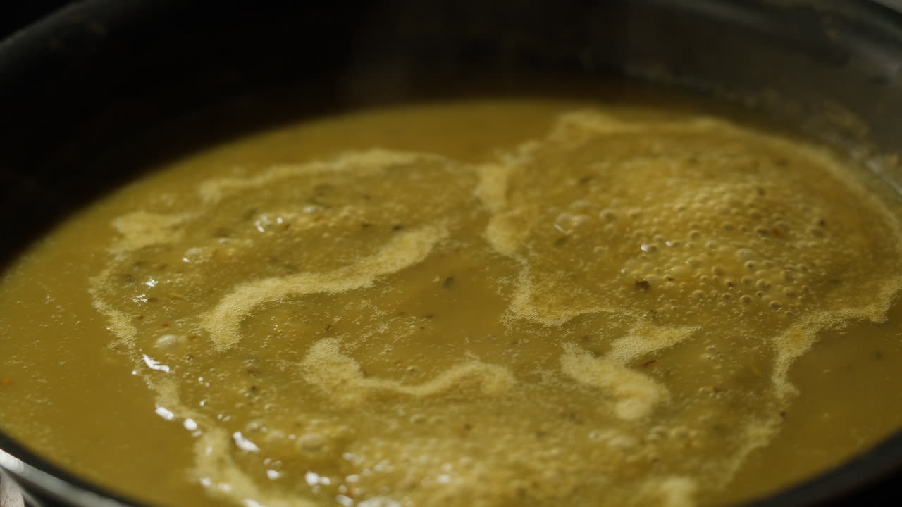 Green boiling sauce texture close-up macro. Cooking green curry with wooden spoon at home.