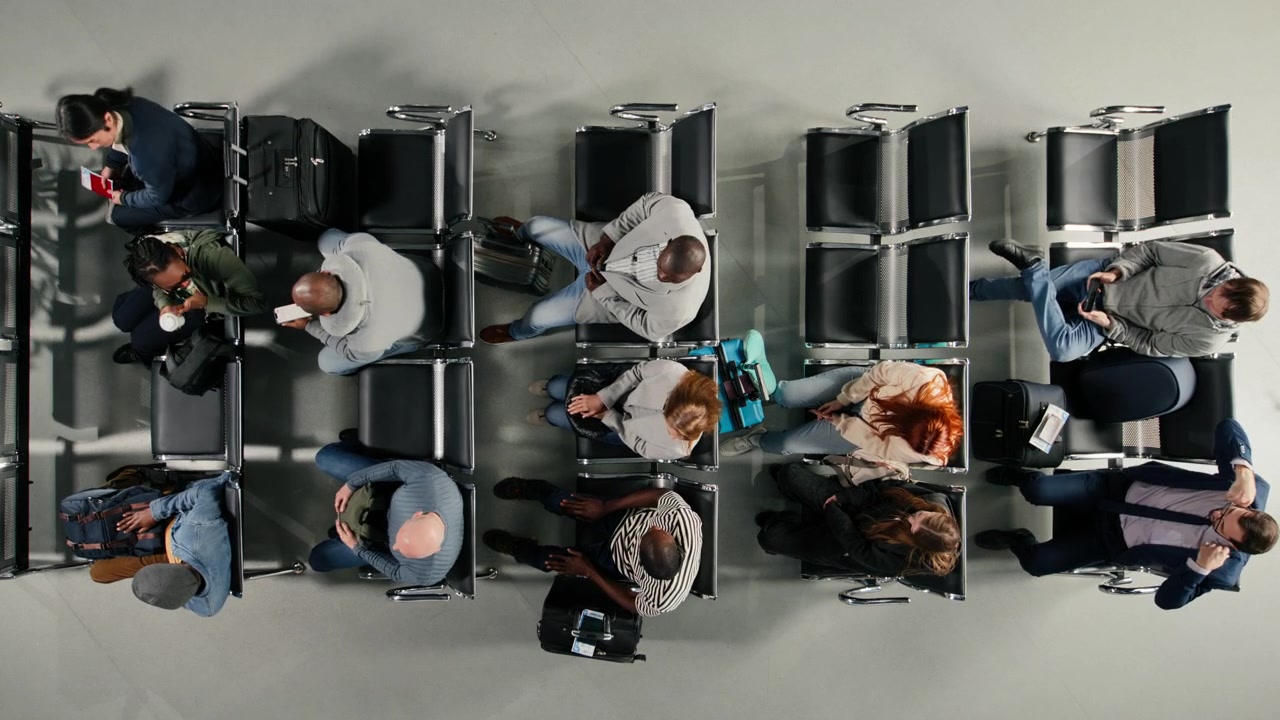 Top down view of diverse tourists in busy airport waiting for vacation flight