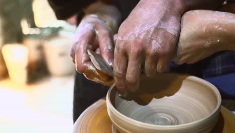 manos dando forma a un cuenco de arcilla en una rueda de cerámica