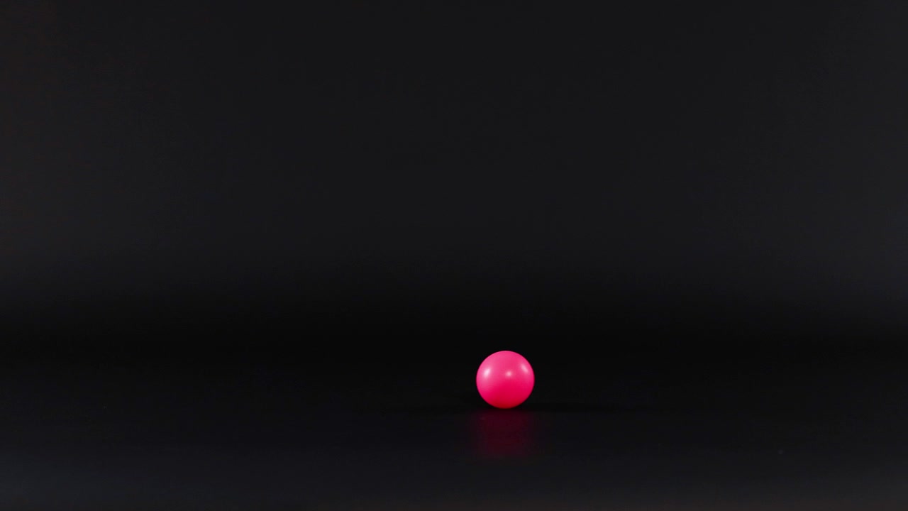 A pink ball rolls across a surface