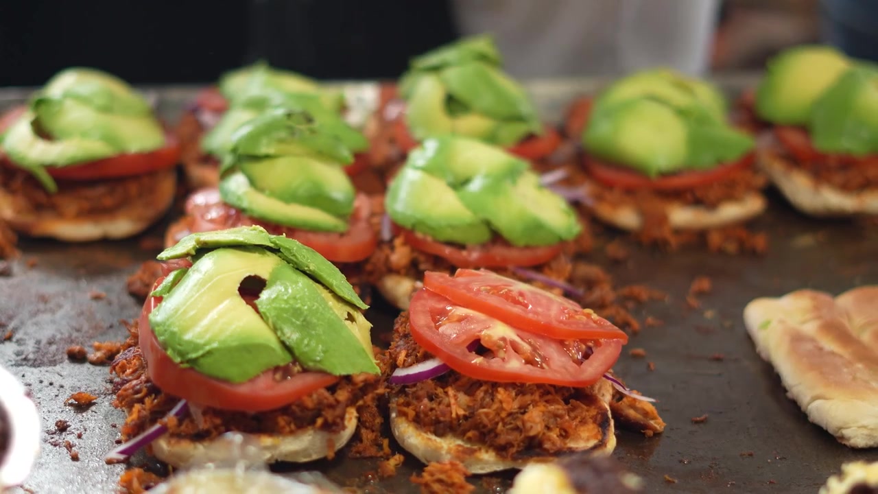 Nærbillede af kok, der tilføjer avocado på en velsmagende mexicansk torta, Mexico