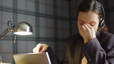 close-up view of a woman working long hours - she takes off her eyeglasses. she has a strong headache.