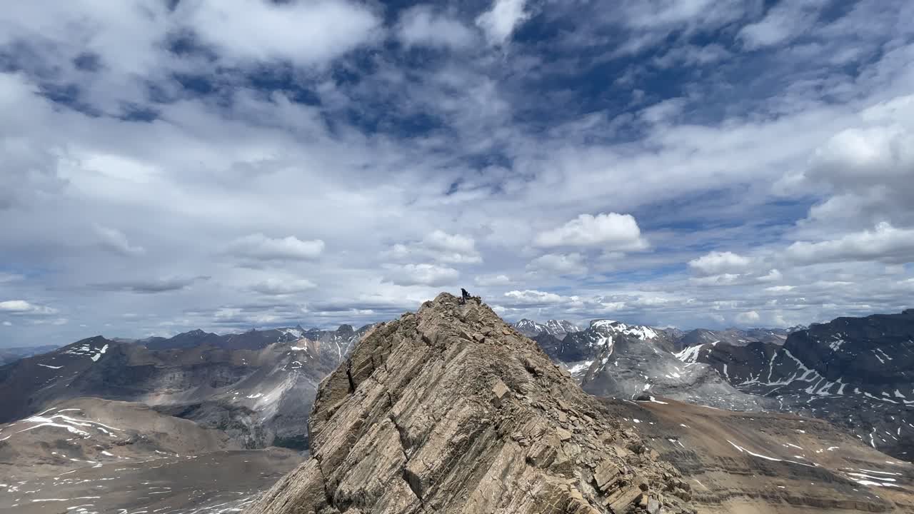 People on a mountain peak at a mountain range at high noon