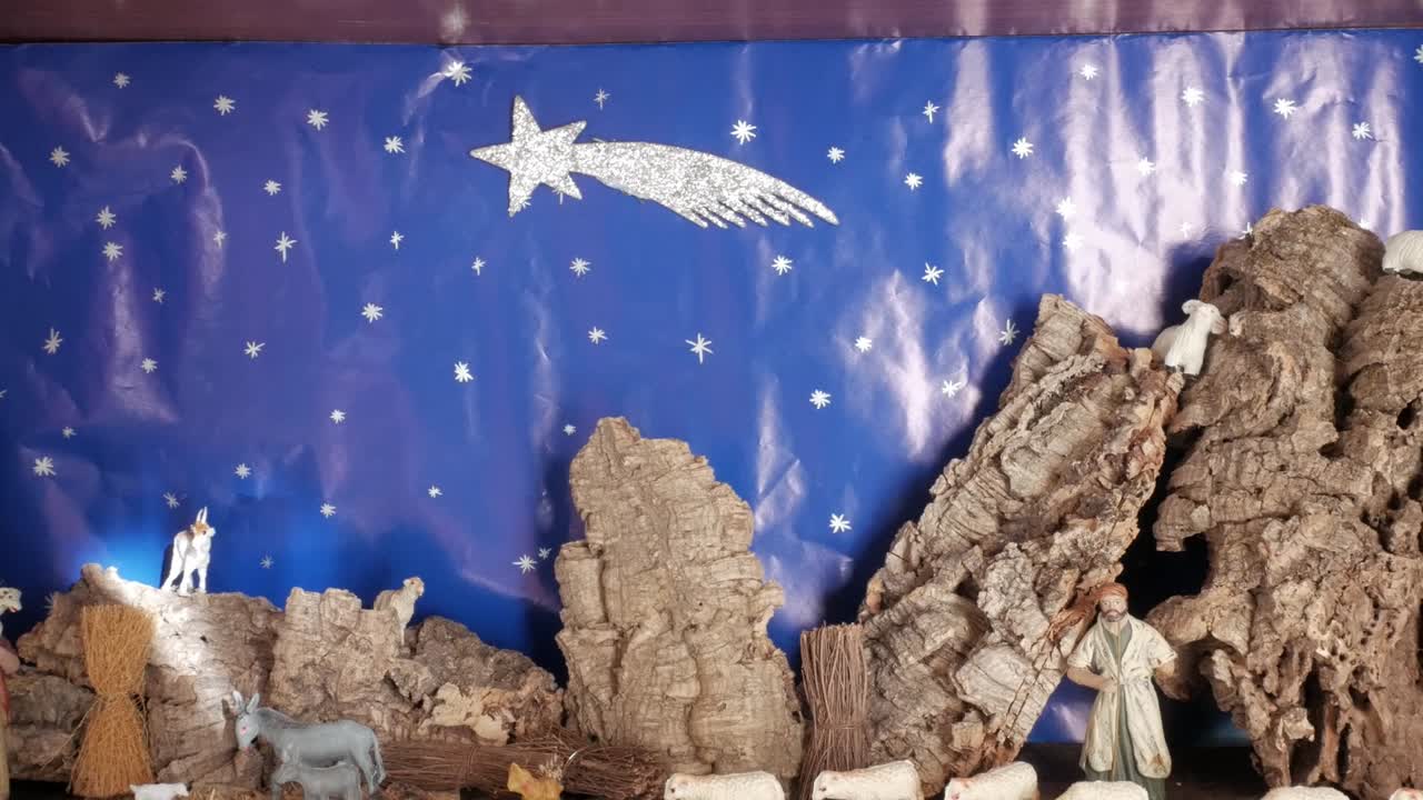 A traditional nativity scene with figures and animals under a night sky with a star