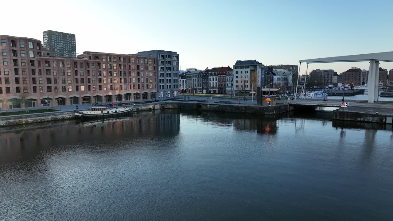 Semi orbit aerial view of Antwerp harbor with modern drawbridge, old buildings, and MAS museum in background at sunset light