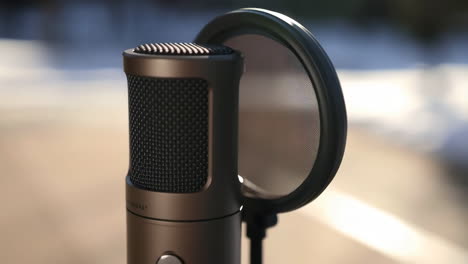 close-up of a professional condenser microphone with pop filter