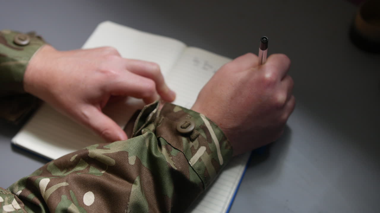 un soldado del ejército marino escribiendo en un informe de libro de diario con una pluma