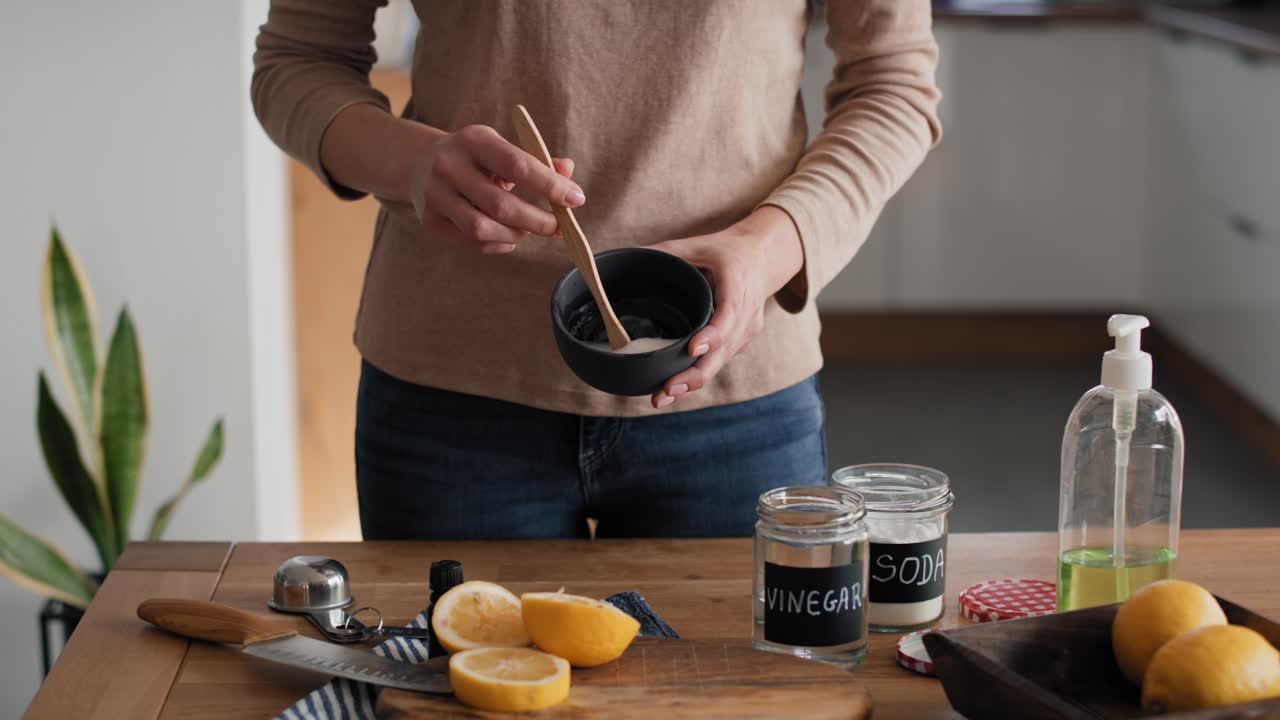 DIYの洗浄剤が入ったボウルにレモン汁を加える顔の見えない人物