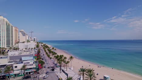 Impresionante-Vista-Aérea-De-La-Costa-De-La-Playa-Con-Edificios-En-El-Lado-Agua-Azul-Cielo-Azul-Palmeras-Ft