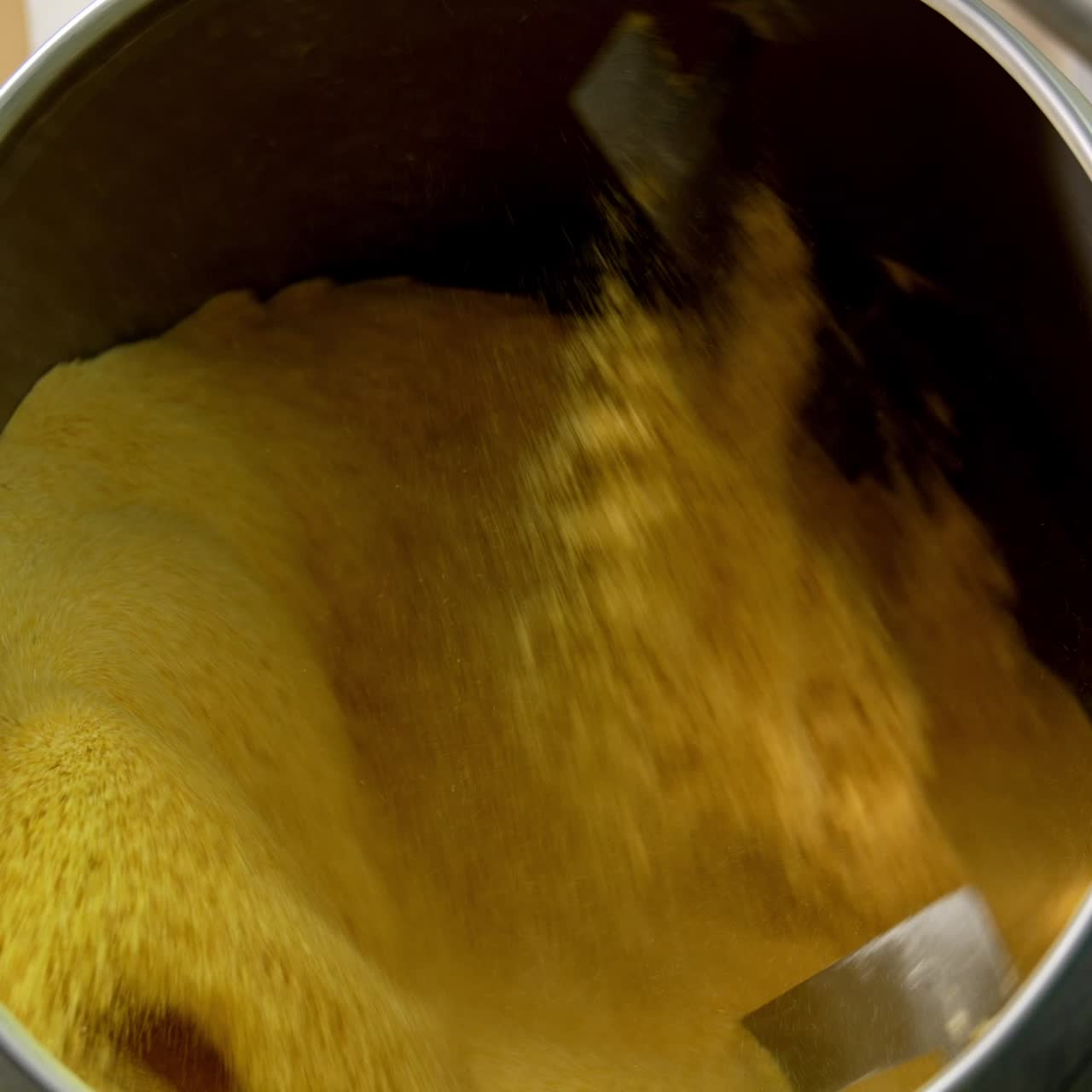 Yellow substance being mixed in a big metal tank. Sweet corn desserts production at the food factory