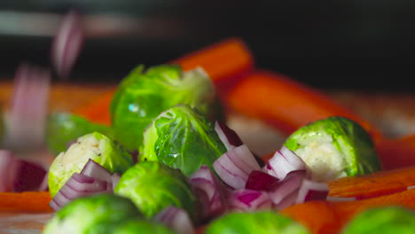 Dropping-chopped-onion-on-to-a-pan-of-brussels-sprouts-and-carrots