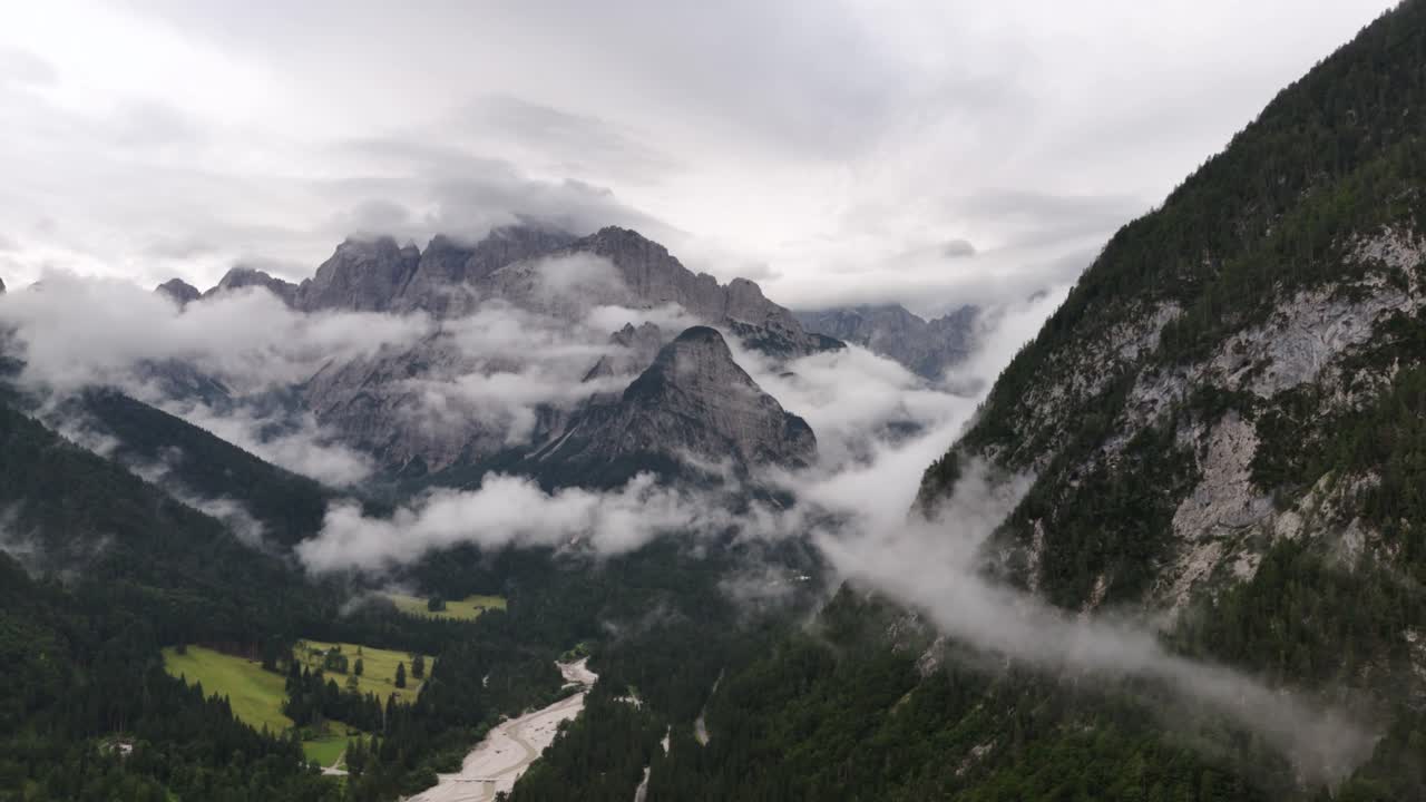 Drone aerial view of clouds drifting over the majestic peaks of the Alps mountains