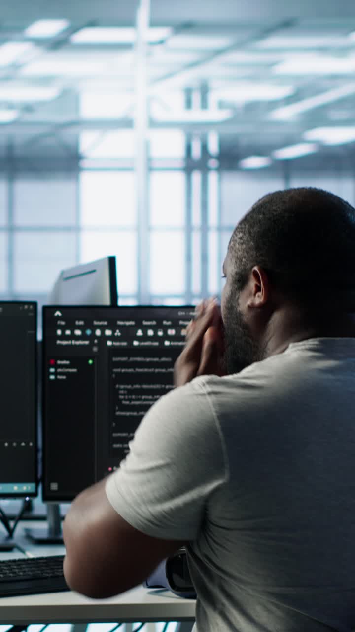 Man Coding on Multiple Computer Screens in Modern Office