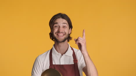 caucasian waiter in front of camera on yellow background.